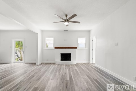 A spacious living room with a fireplace and a ceiling fan.