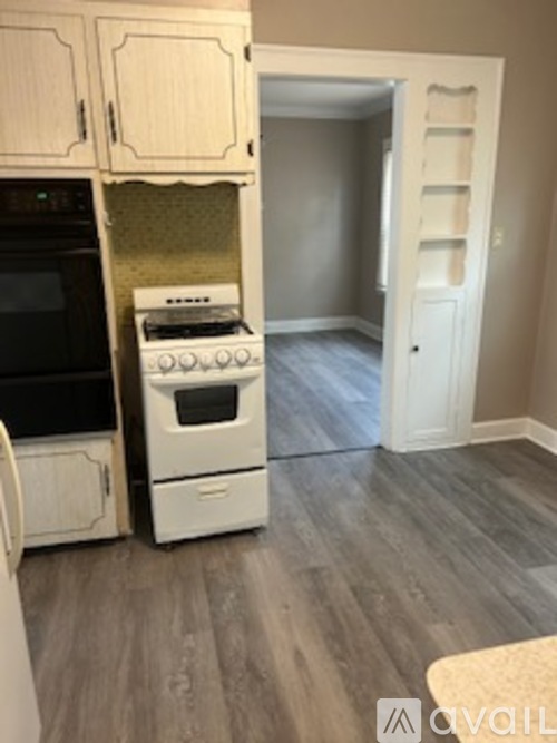 A kitchen with a white oven and black microwave.