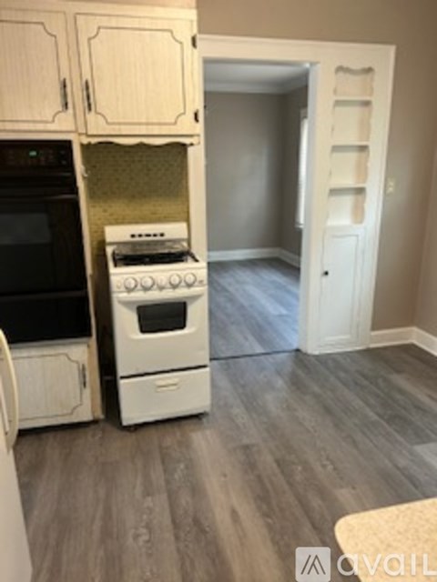 A kitchen with a white oven and black microwave.