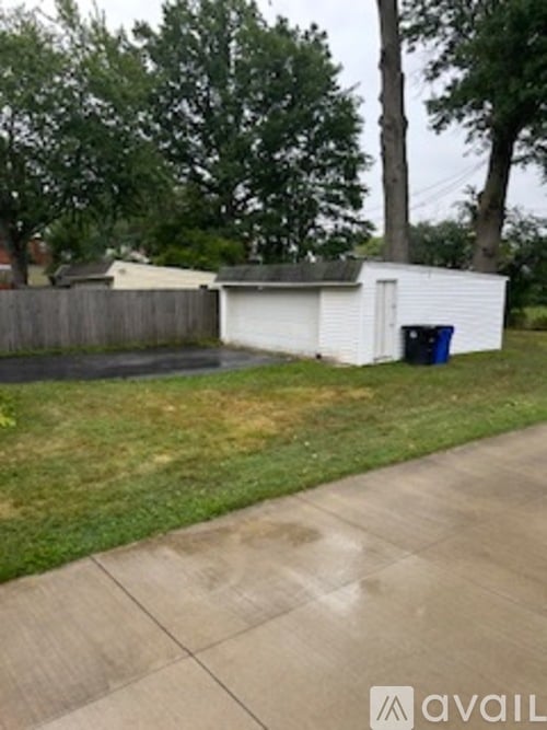 A white shed sits in a grassy backyard.