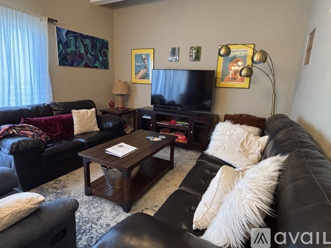 A living room with black leather couches and a wooden coffee table.