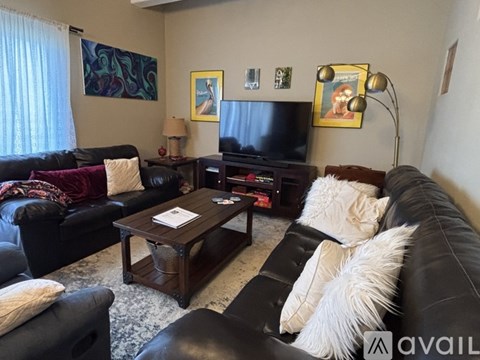 A living room with black leather couches and a wooden coffee table.
