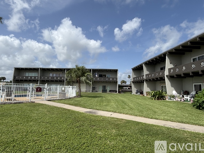 A grassy area in front of a building with a clear blue sky above.