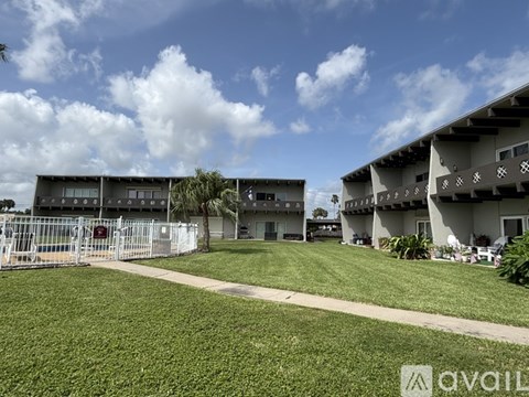 A grassy area in front of a building with a clear blue sky above.