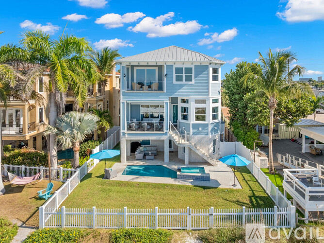 A large house with a pool surrounded by a white fence.