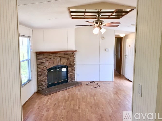 A living room with a fireplace and a ceiling fan.