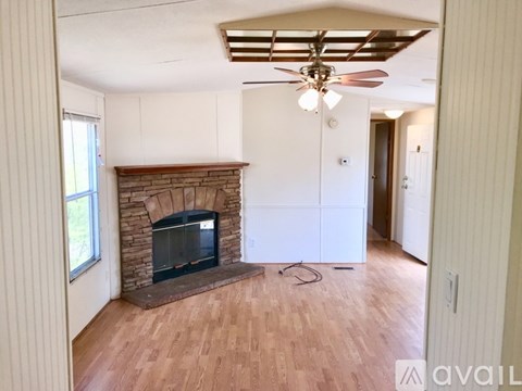 A living room with a fireplace and a ceiling fan.