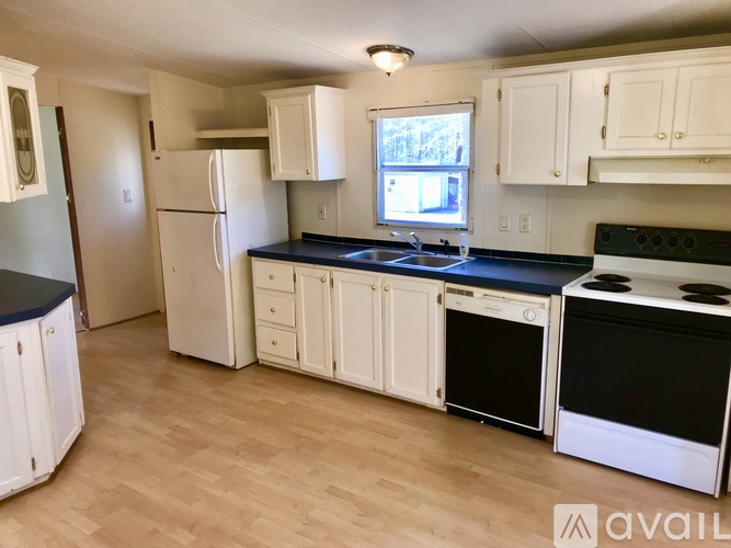 A kitchen with white cabinets and black countertops.