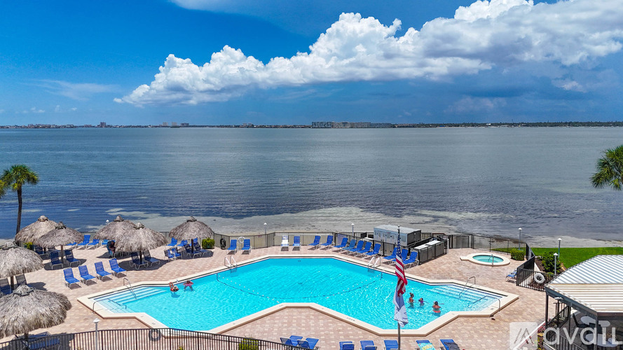 A large swimming pool with a fence around it and people swimming in it.