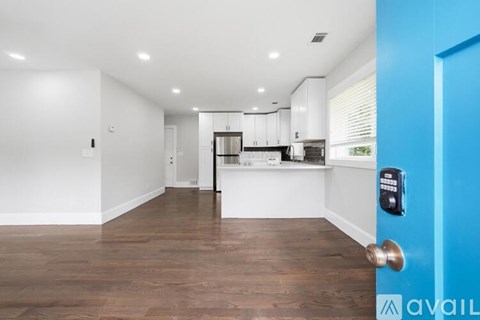 A modern kitchen with white cabinets and a blue door.