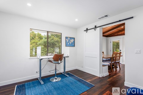 A room with a blue rug and a brown chair.