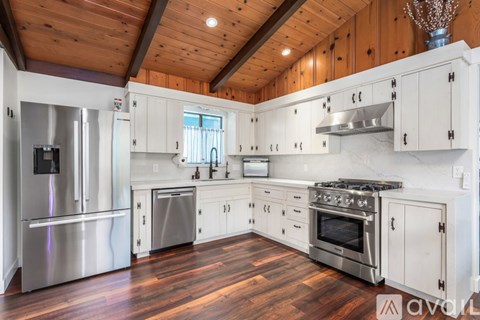 A kitchen with wooden ceiling and white cabinets.