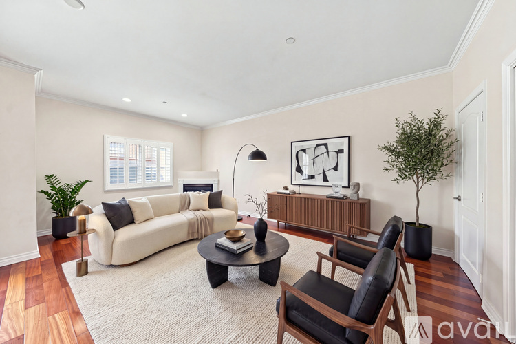 A living room with a white couch, a black chair, and a wooden cabinet.