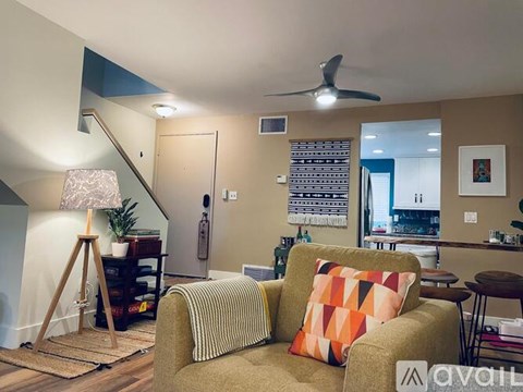 A living room with a striped couch and a fan on the ceiling.