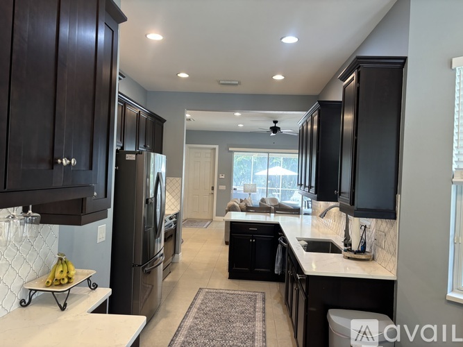 A kitchen with black cabinets and a refrigerator.