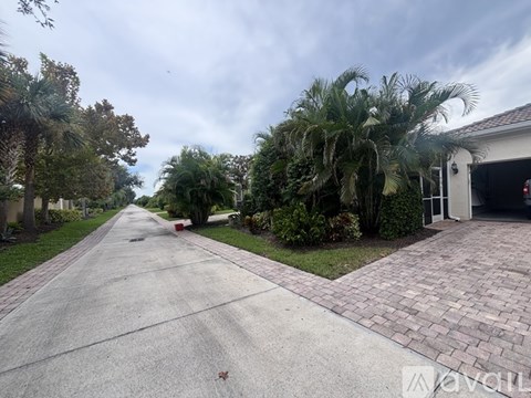 A residential driveway with a house and palm trees on the side.