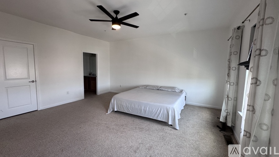 A bedroom with a bed, a ceiling fan, and a door.
