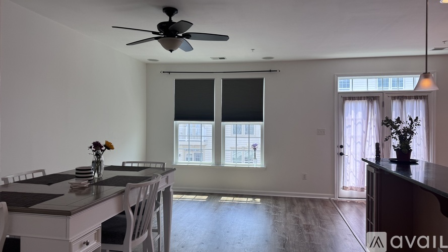 A dining room with a table set for two and a ceiling fan.
