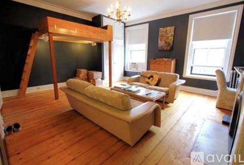 A living room with a couch, a chair, and a wooden floor.