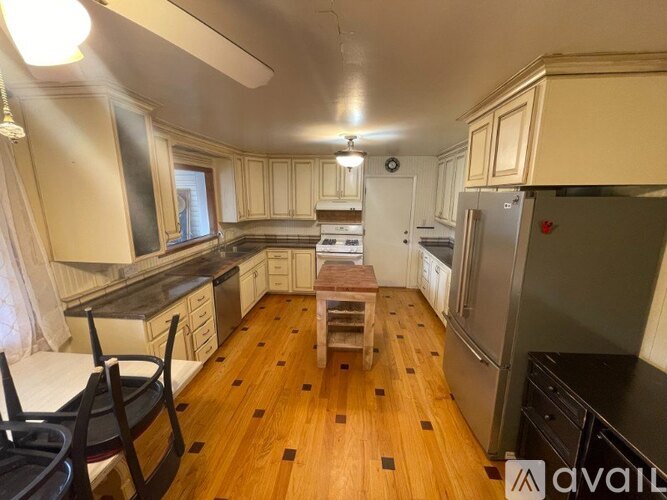 A kitchen with wooden floors and a refrigerator on the right.