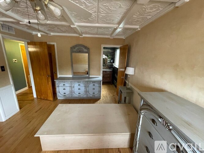 A room with a bed, a dresser, and a mirror.