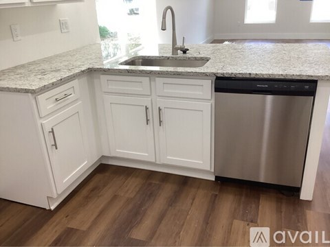 A kitchen with white cabinets and a granite countertop.