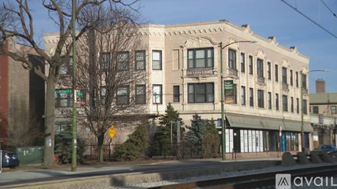 A street view of a large building with a green sign in front of it.