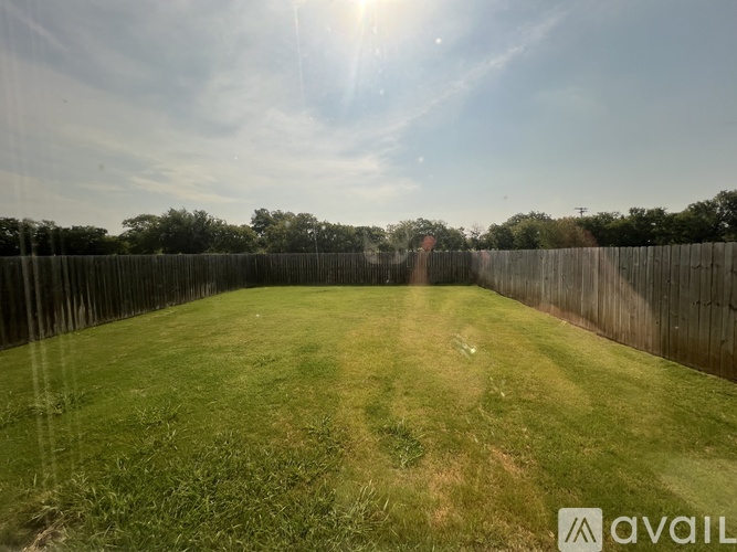 A backyard with a wooden fence and a grassy field.