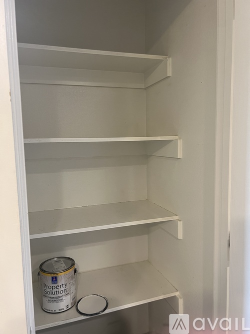 A white shelving unit with a can of Property Solutions on the bottom shelf.
