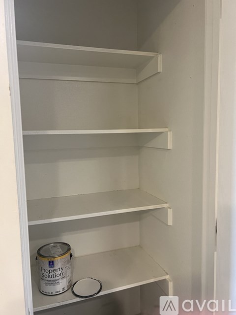 A white shelving unit with a can of Property Solutions on the bottom shelf.