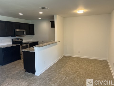 A kitchen with black cabinets and a granite countertop.