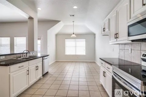A kitchen with white cabinets and black countertops.