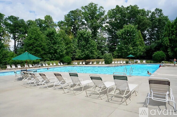 A pool surrounded by trees and chairs.