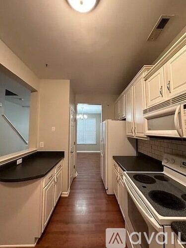 A kitchen with white cabinets and black countertops.