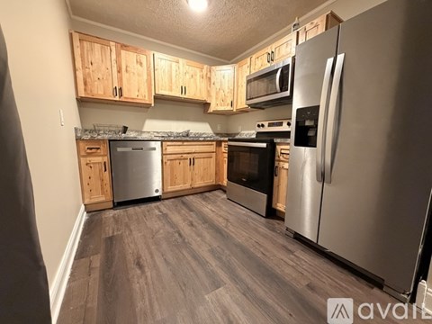 A kitchen with wooden cabinets and a stainless steel refrigerator.