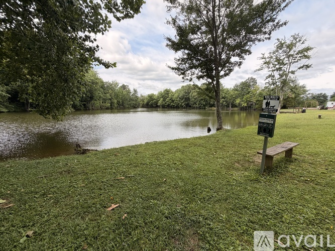 A park with a bench and a signpost by the water.
