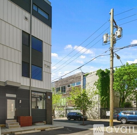 A modern building with a grey facade and a blue car parked in front.