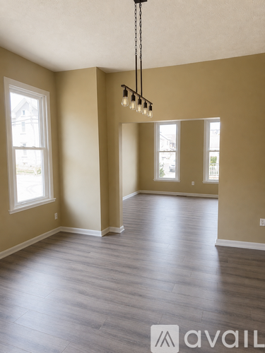 A room with wooden floors and a chandelier hanging from the ceiling.