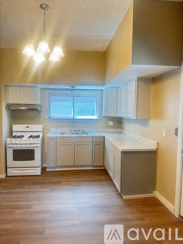 A kitchen with a white stove and cabinets.