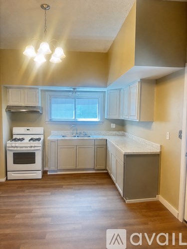 A kitchen with a white stove and cabinets.