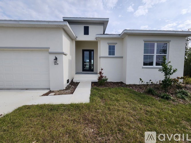 A white house with a black door and windows is for sale.