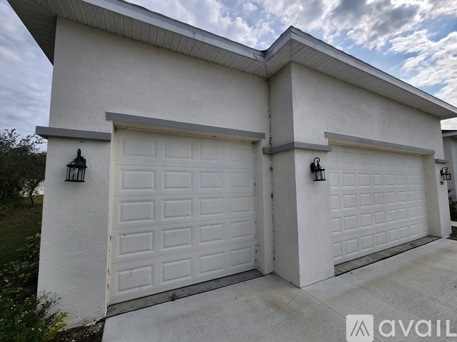 A white house with two garages and a logo that reads "AVAIL" on the garage doors.