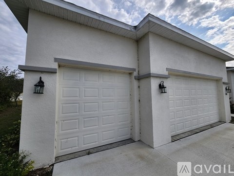 A white house with two garages and a logo that reads "AVAIL" on the garage doors.