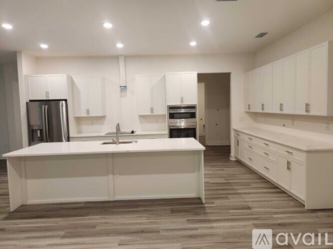 A kitchen with white cabinets and a wooden floor.