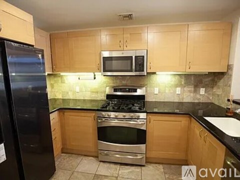 A kitchen with wooden cabinets and a black refrigerator.