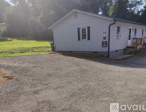 A small white building with the number 517 on it is surrounded by a gravel lot.