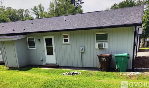 A small house with a grey roof and a green lawn in front.