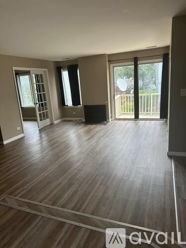 A spacious room with wooden flooring and sliding glass doors.