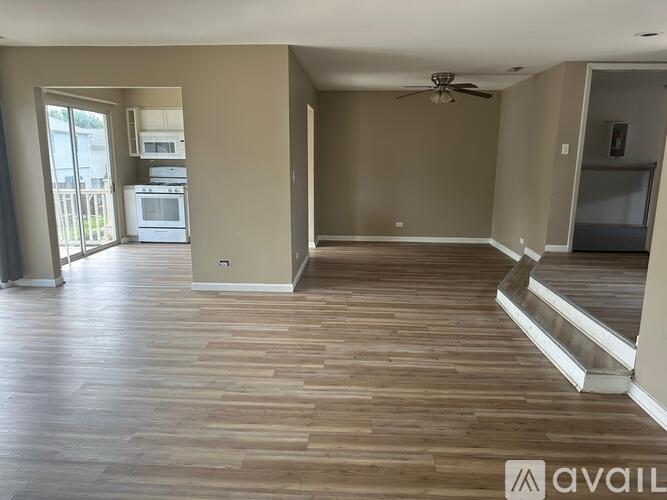 A spacious living room with a wood floor and a ceiling fan.