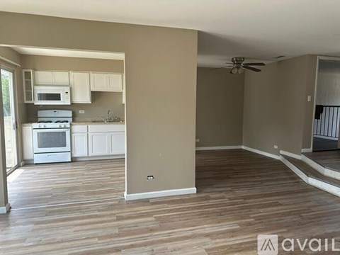 A kitchen with white appliances and wooden floors.